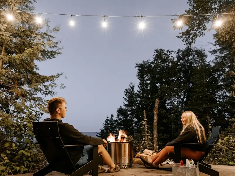 Couple relaxing by a fire pit under string lights